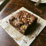 Delicious banana bread brownies topped with nuts and chocolate chips.